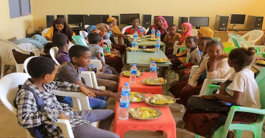 Children in Afar receiving breakfast and educational materials through the Food for School program